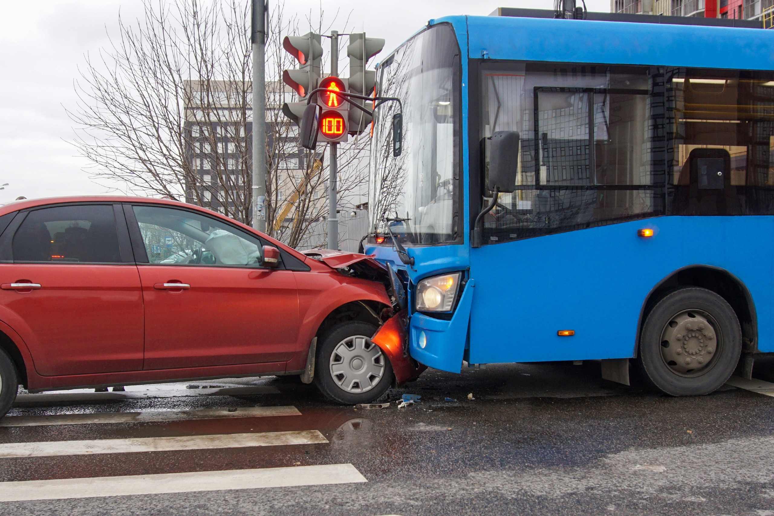 City bus colliding with a red car at an intersection, depicting a serious traffic crash handled by a bus accident lawyer in Spokane.
