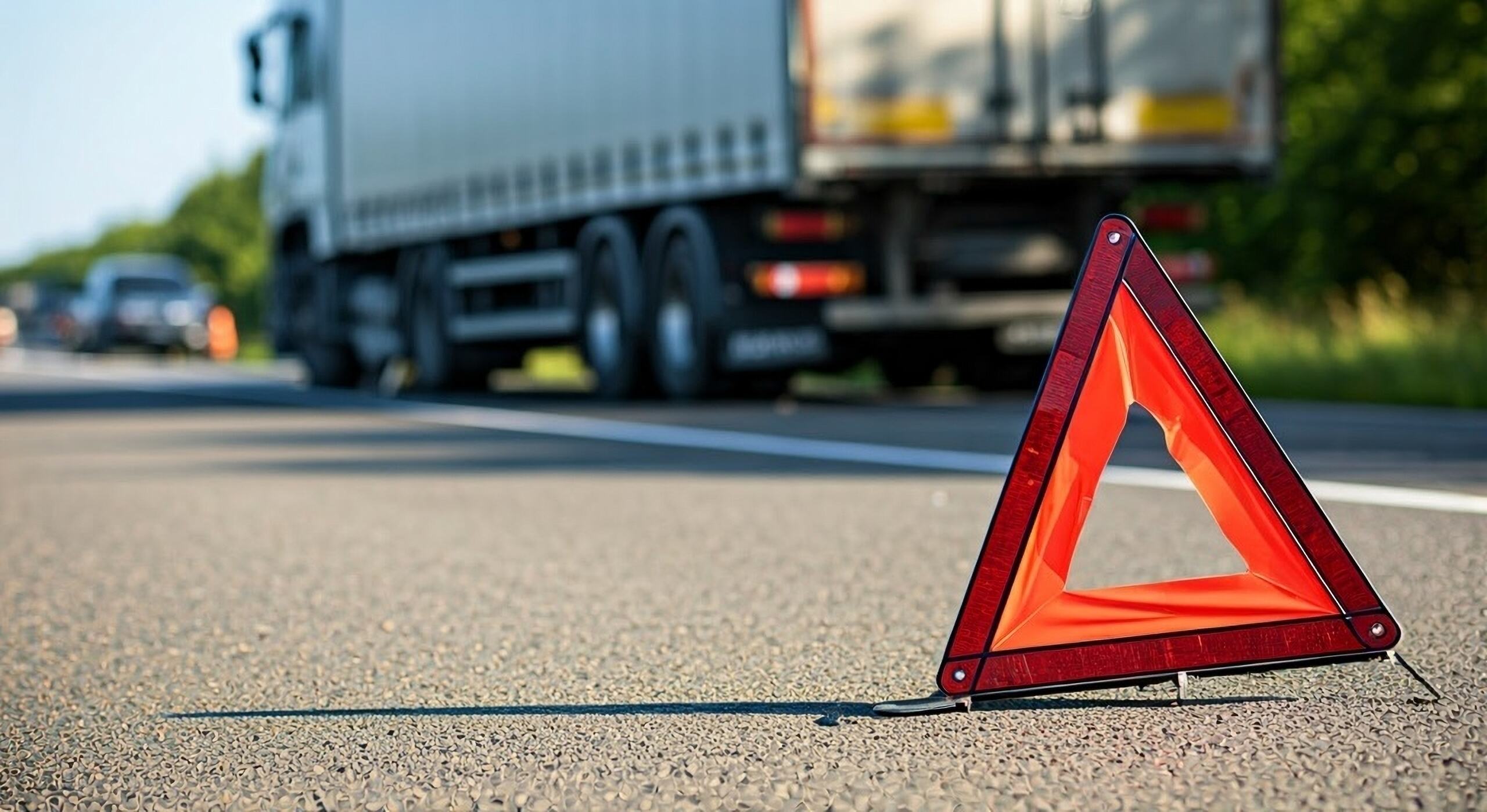 Warning triangle on a Washington roadway after a truck crash, highlighting the complexity of truck accidents and why hire a truck accident lawyer.