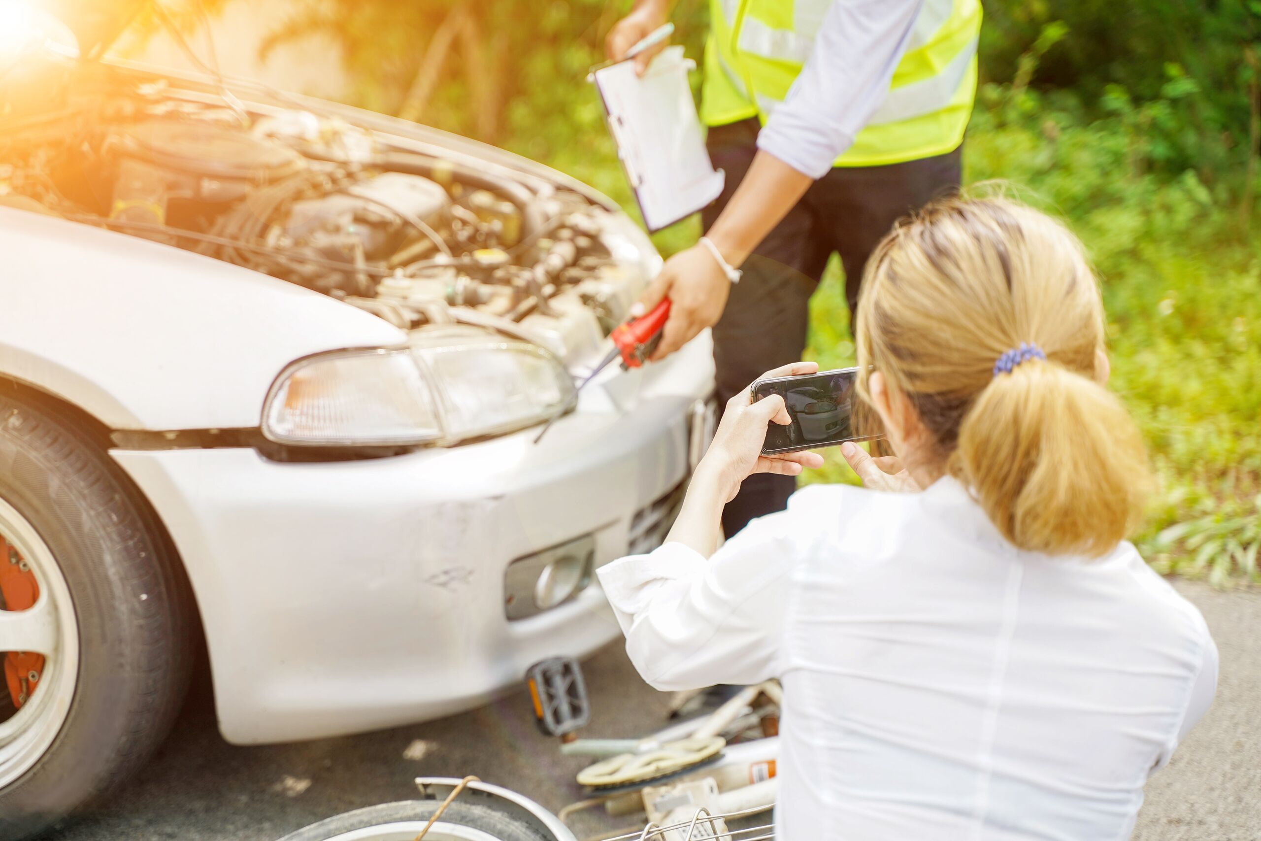 A woman taking photos of a car crash in Washington to satisfy insurance notification requirements without giving a recorded statement.