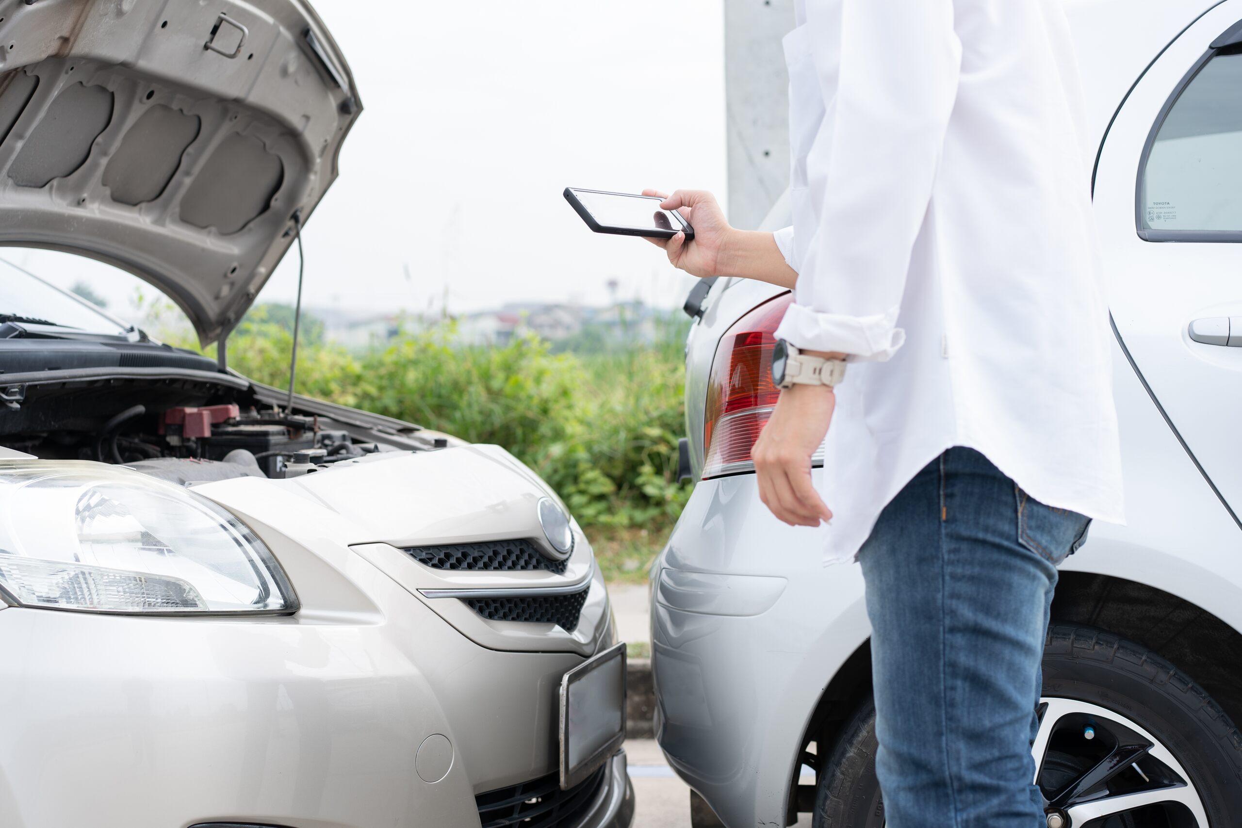 A person using a smartphone to photograph vehicle damage and a license plate, demonstrating the critical evidence preservation needed within the first 30 days of a Spokane car accident.