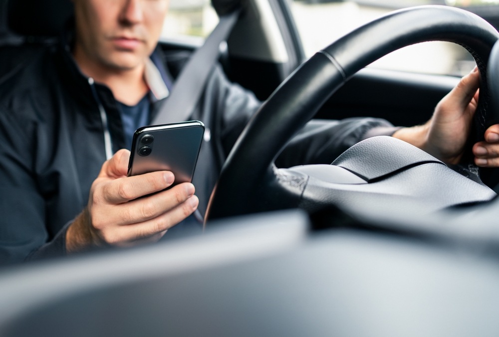 Rideshare driver checking phone while driving, a common insurance gap risk in Spokane Uber and Lyft accidents