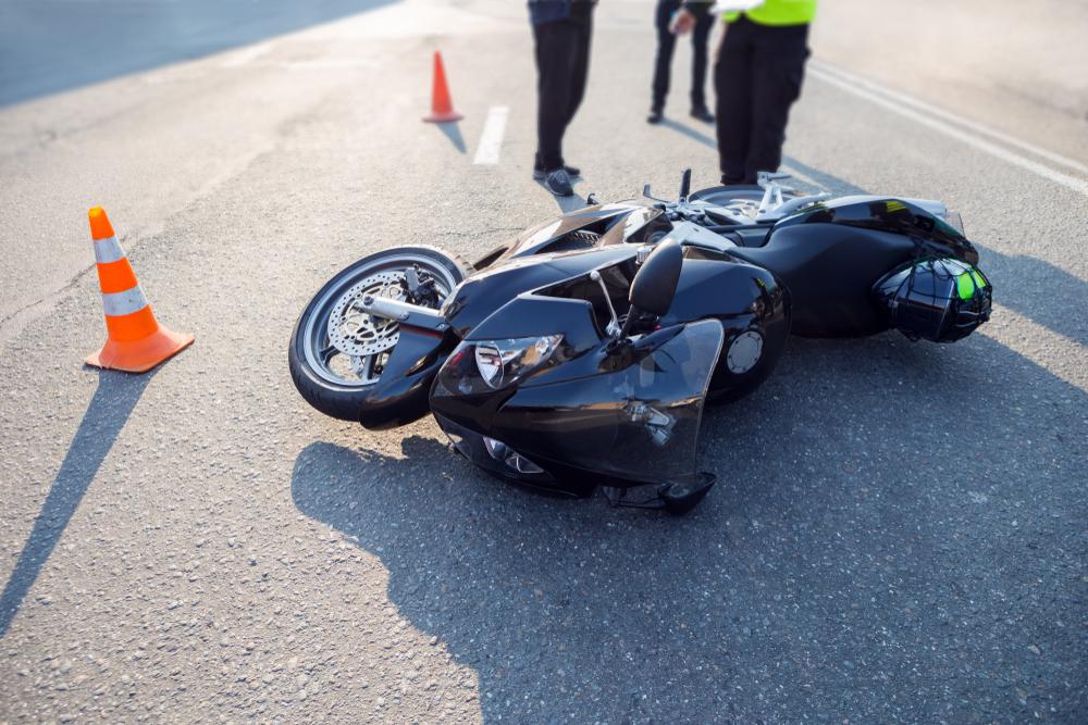 Police investigating a motorcycle accident scene, where fault determination affects assumption of risk defenses