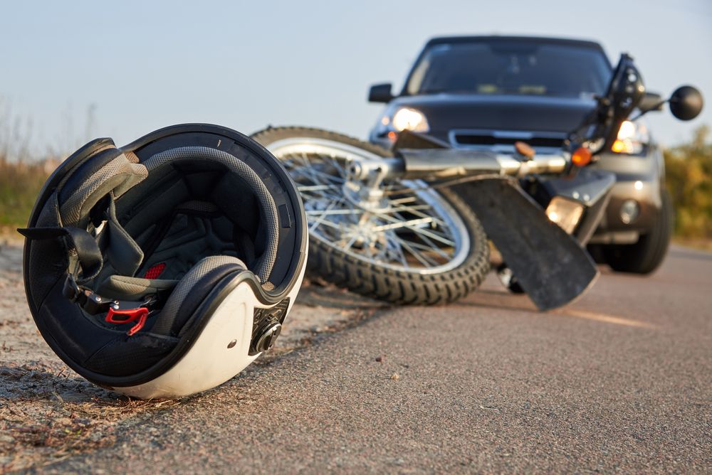 Damaged motorcycle helmet beside crash wreckage, illustrating why every case's value differs from the average