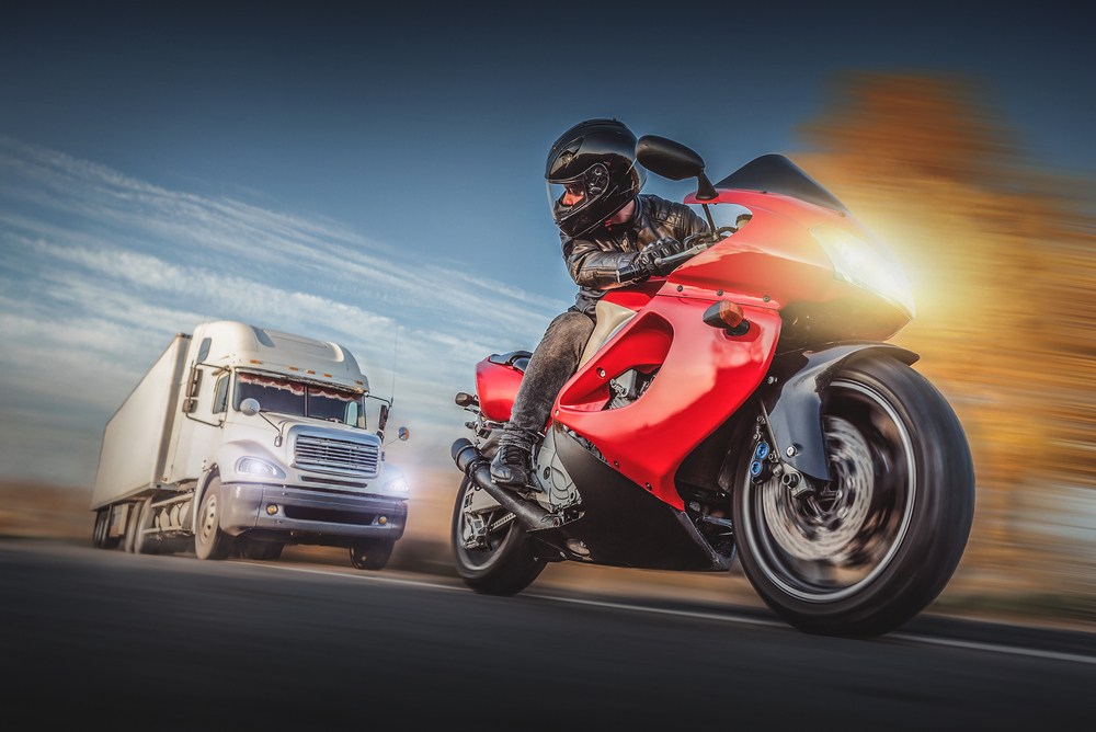 Motorcyclist riding near a semi truck, the kind of high-risk scenario that can drive settlement value above average